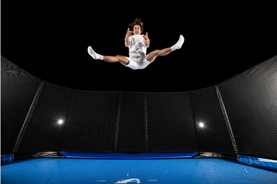 An individual is captured mid-air, jumping on a trampoline, embodying a sense of freedom and playful energy.